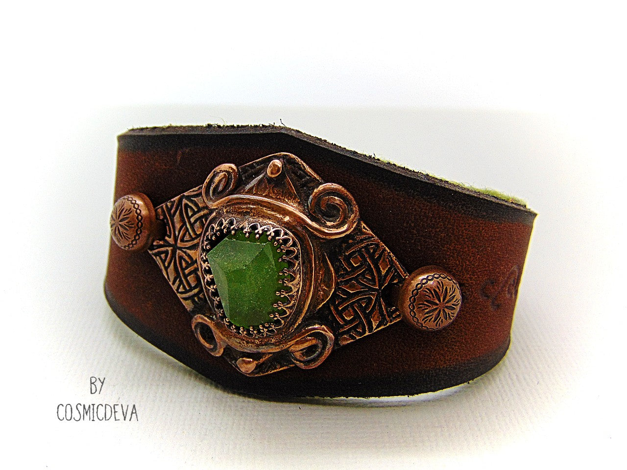 One of a kind handcrafted leather cuff bracelet made of hand cut earthy brown dyed veg tan leather. The focal point is a high quality natural raw green peridot gemstone in a bezel setting on a Celtic design textured solid copper base. The inside of the leather bracelet is lined with olive green felt for your comfort. Cosmicdeva