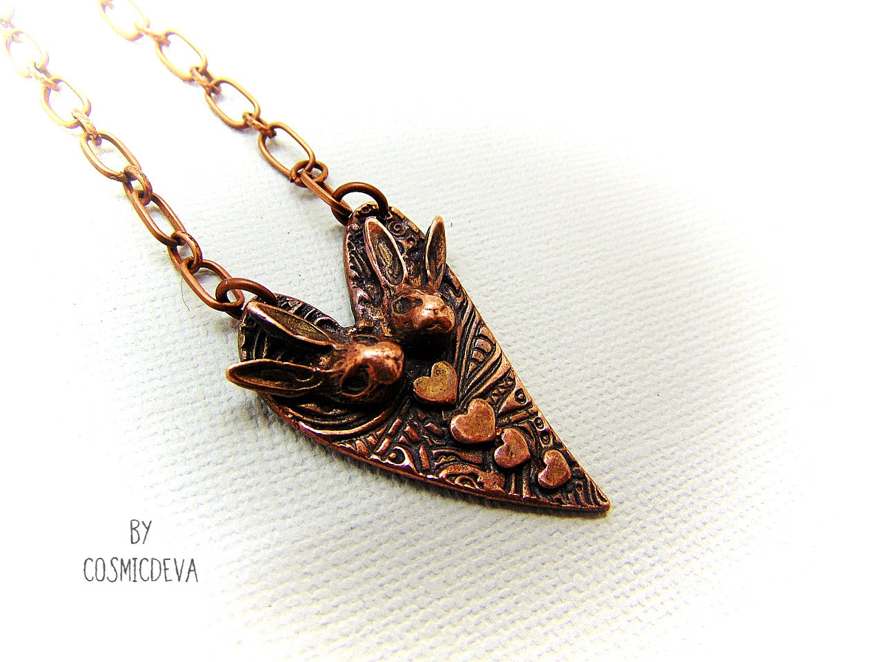 Cute one of a kind handmade unique bunny love heart pendant necklace. This rabbit pendant is heart shaped with to bunny heads and lots of tiny hearts. This gorgeous copper bunny heart pendant balances from a 18-inch – 21 inches chain with a copper lobster clasp closure. The pendant is hallmarked with the cosmicdeva logo on the backside. The wearable bunny art copper jewelry piece was oxidized for a deep warm finish and was sealed with renaissance wax.