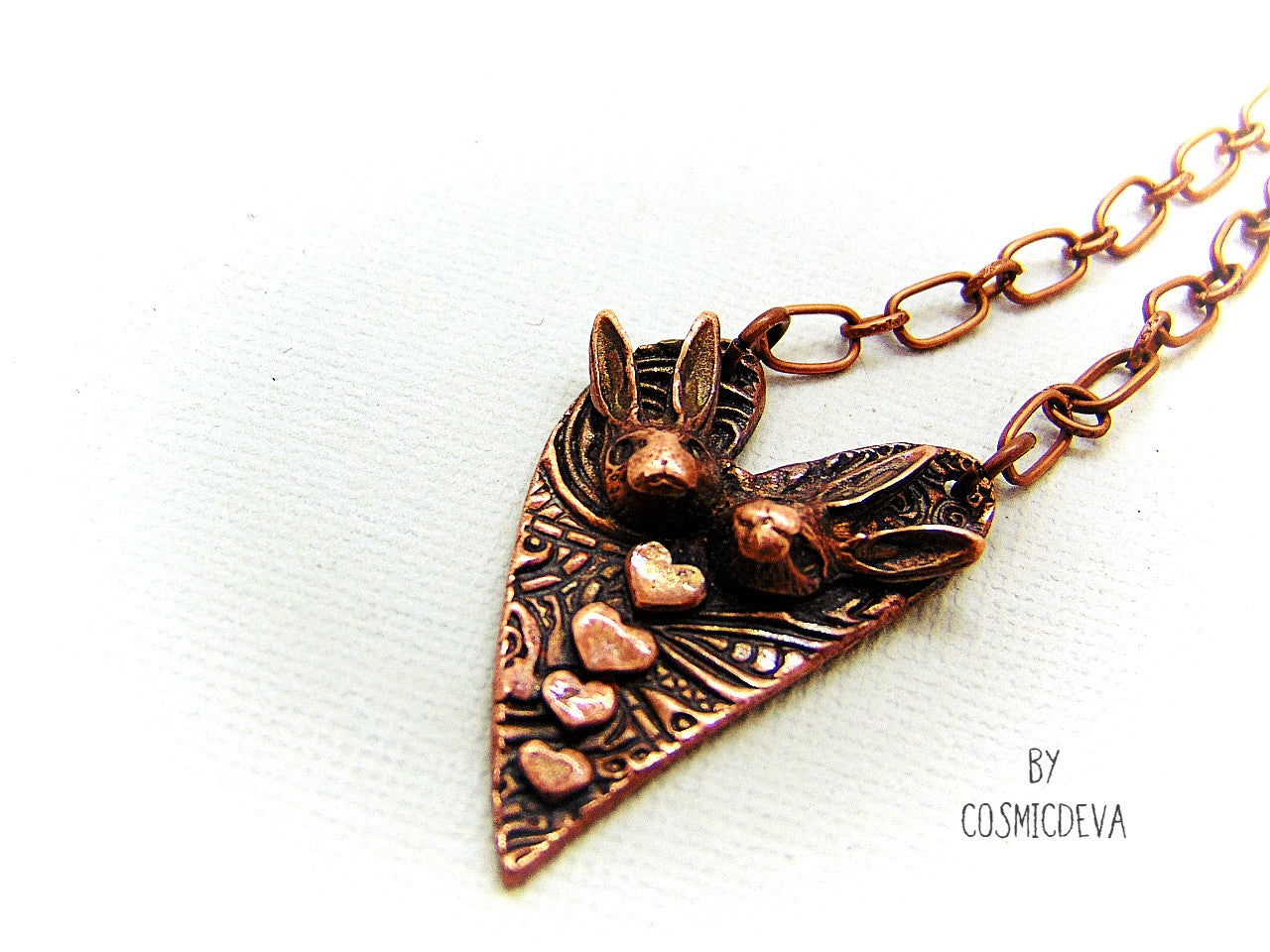 Cute one of a kind handmade unique bunny love heart pendant necklace. This rabbit pendant is heart shaped with to bunny heads and lots of tiny hearts. This gorgeous copper bunny heart pendant balances from a 18-inch – 21 inches chain with a copper lobster clasp closure. The pendant is hallmarked with the cosmicdeva logo on the backside. The wearable bunny art copper jewelry piece was oxidized for a deep warm finish and was sealed with renaissance wax.