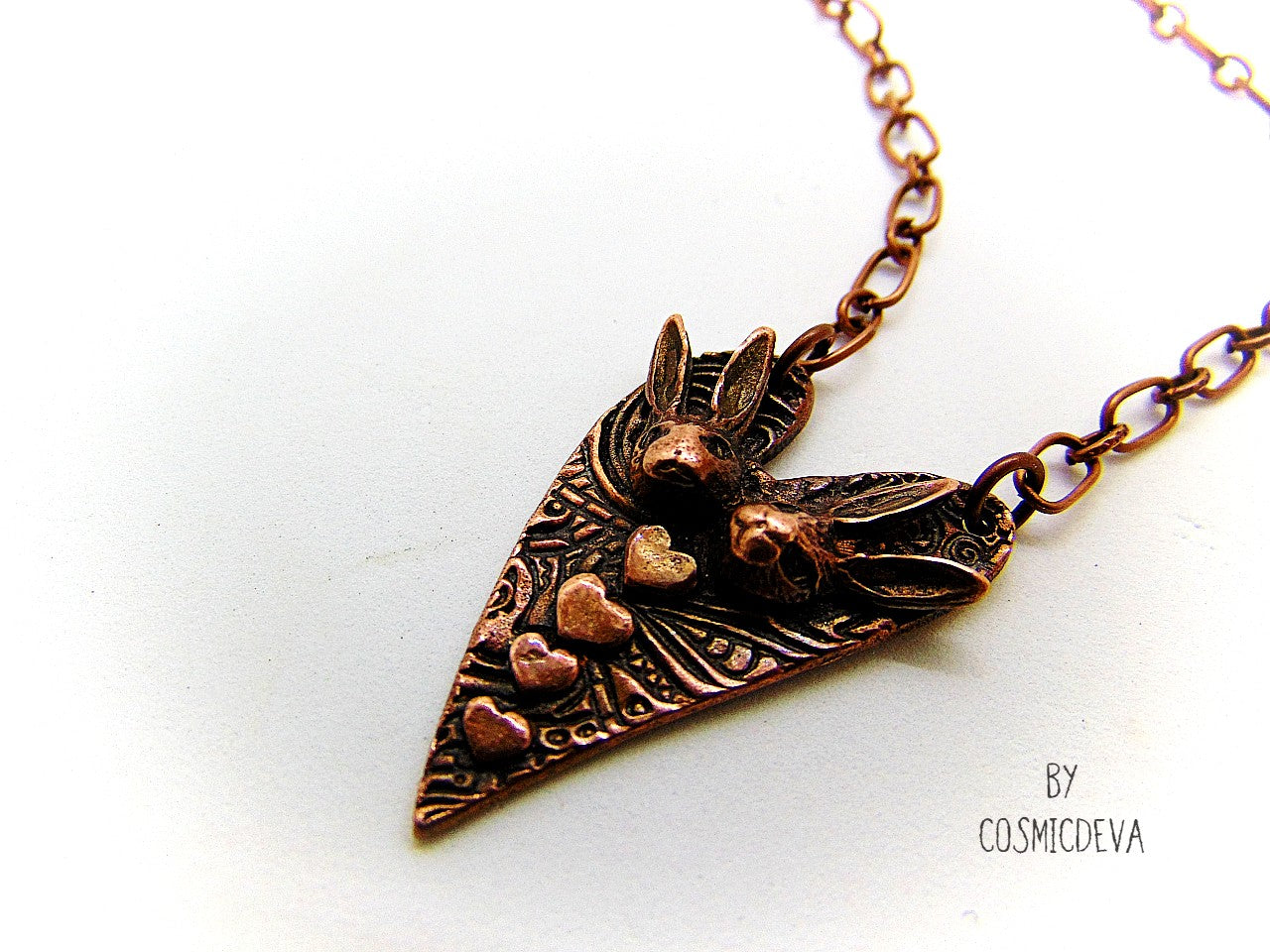 Cute one of a kind handmade unique bunny love heart pendant necklace. This rabbit pendant is heart shaped with to bunny heads and lots of tiny hearts. This gorgeous copper bunny heart pendant balances from a 18-inch – 21 inches chain with a copper lobster clasp closure. The pendant is hallmarked with the cosmicdeva logo on the backside. The wearable bunny art copper jewelry piece was oxidized for a deep warm finish and was sealed with renaissance wax.