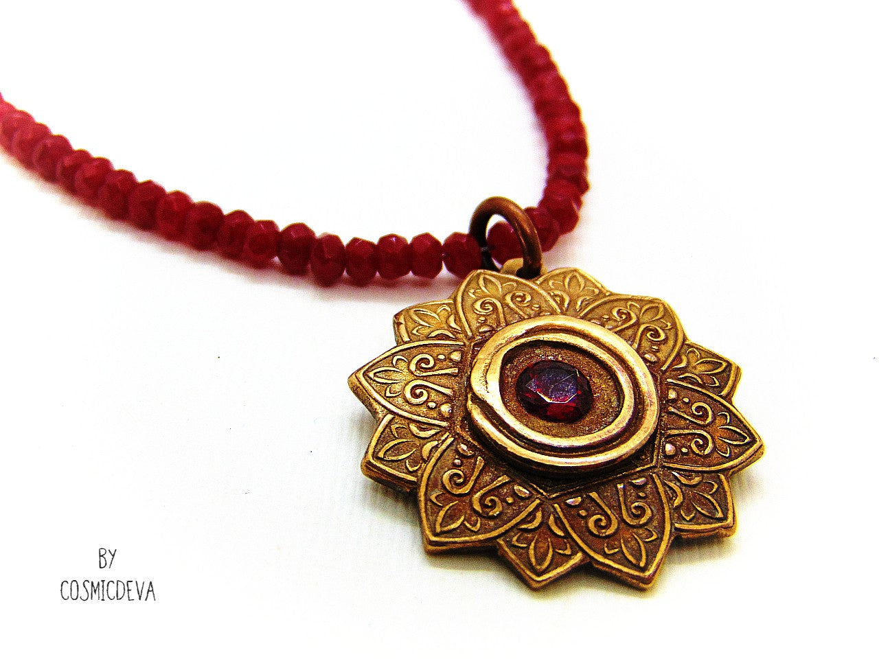 Celebrate your spiritual side with this unique Red Ruby Mandala Mendhi Gold Bronze Necklace. Crafted with a hand-formed bronze pendant, a stunning faceted lab-created ruby gemstone, and adorned with small red jade rondelle beads, this one of a kind necklace is an inspired homage to Indian Mehndi culture. Fall in love with the beauty and mystery of this spiritual accessory!
