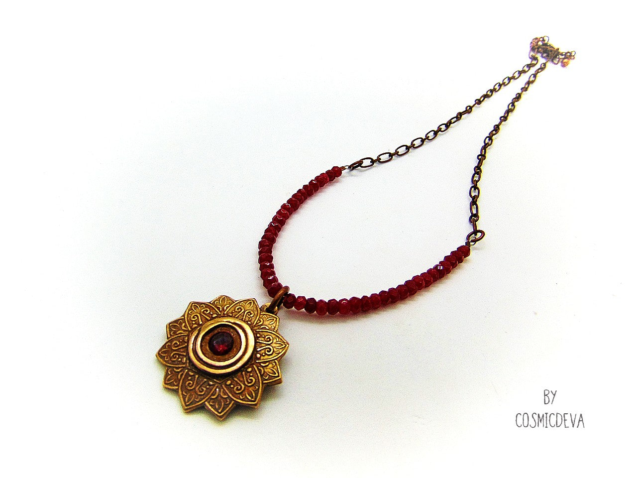 Celebrate your spiritual side with this unique Red Ruby Mandala Mendhi Gold Bronze Necklace. Crafted with a hand-formed bronze pendant, a stunning faceted lab-created ruby gemstone, and adorned with small red jade rondelle beads, this one of a kind necklace is an inspired homage to Indian Mehndi culture. Fall in love with the beauty and mystery of this spiritual accessory!