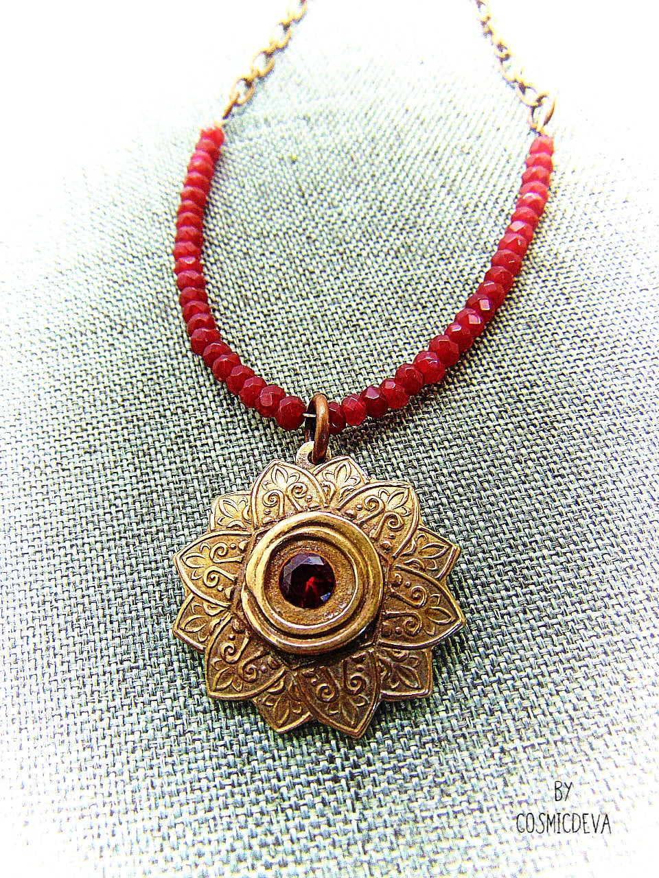 Celebrate your spiritual side with this unique Red Ruby Mandala Mendhi Gold Bronze Necklace. Crafted with a hand-formed bronze pendant, a stunning faceted lab-created ruby gemstone, and adorned with small red jade rondelle beads, this one of a kind necklace is an inspired homage to Indian Mehndi culture. Fall in love with the beauty and mystery of this spiritual accessory!