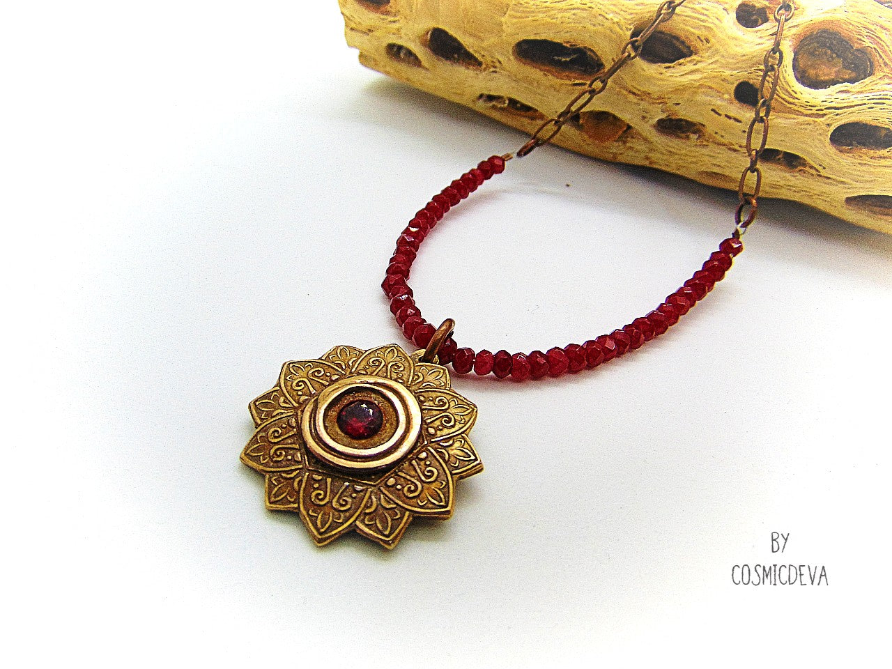 Celebrate your spiritual side with this unique Red Ruby Mandala Mendhi Gold Bronze Necklace. Crafted with a hand-formed bronze pendant, a stunning faceted lab-created ruby gemstone, and adorned with small red jade rondelle beads, this one of a kind necklace is an inspired homage to Indian Mehndi culture. Fall in love with the beauty and mystery of this spiritual accessory!
