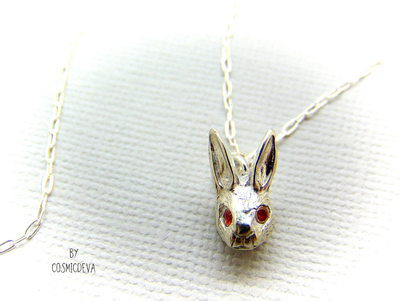 Handmade dainty small little rabbit 🐰 made of solid sterling silver with tiny faceted lab created fire opal eyes. Lab created stones are chemically, physically and optically identical to those mined underground. This cute little bunny dangles from a delicate 18 inch solid .925 sterling silver flat cable 1.4mm chain necklace.