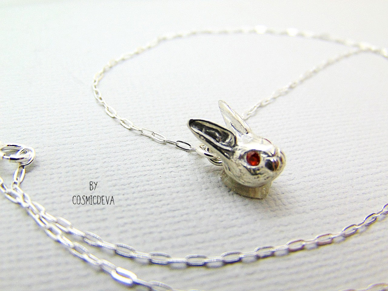 Handmade dainty small little rabbit 🐰 made of solid sterling silver with tiny faceted lab created fire opal eyes. Lab created stones are chemically, physically and optically identical to those mined underground. This cute little bunny dangles from a delicate 18 inch solid .925 sterling silver flat cable 1.4mm chain necklace.