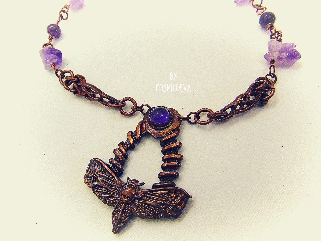 Handcrafted detailed death head hawk Moth (Acherontia) made of solid copper with a natural amethyst cabochon setting. The pendant is the focal point of a chain necklace with drilled natural raw amethyst gemstones, natural amethyst round beads and two completely handcrafted copper Celtic knot design findings.