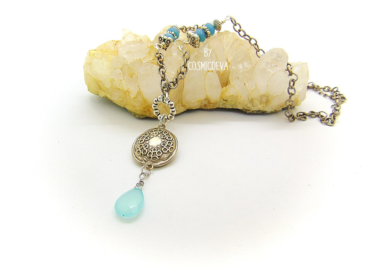 Beautiful handmade silver bronze lentil pendant with a mandala texture and a large faceted briolette aqua blue chalcedony gemstone dangle bead. The large hand formed lentil bead is double sided with two different designs and so can be worn facing either side. The pendant suspends from an 18 inch – 20-inch-long chain with accentual faceted Brazilian aquamarine abacus beads and Tibetan silver beads.