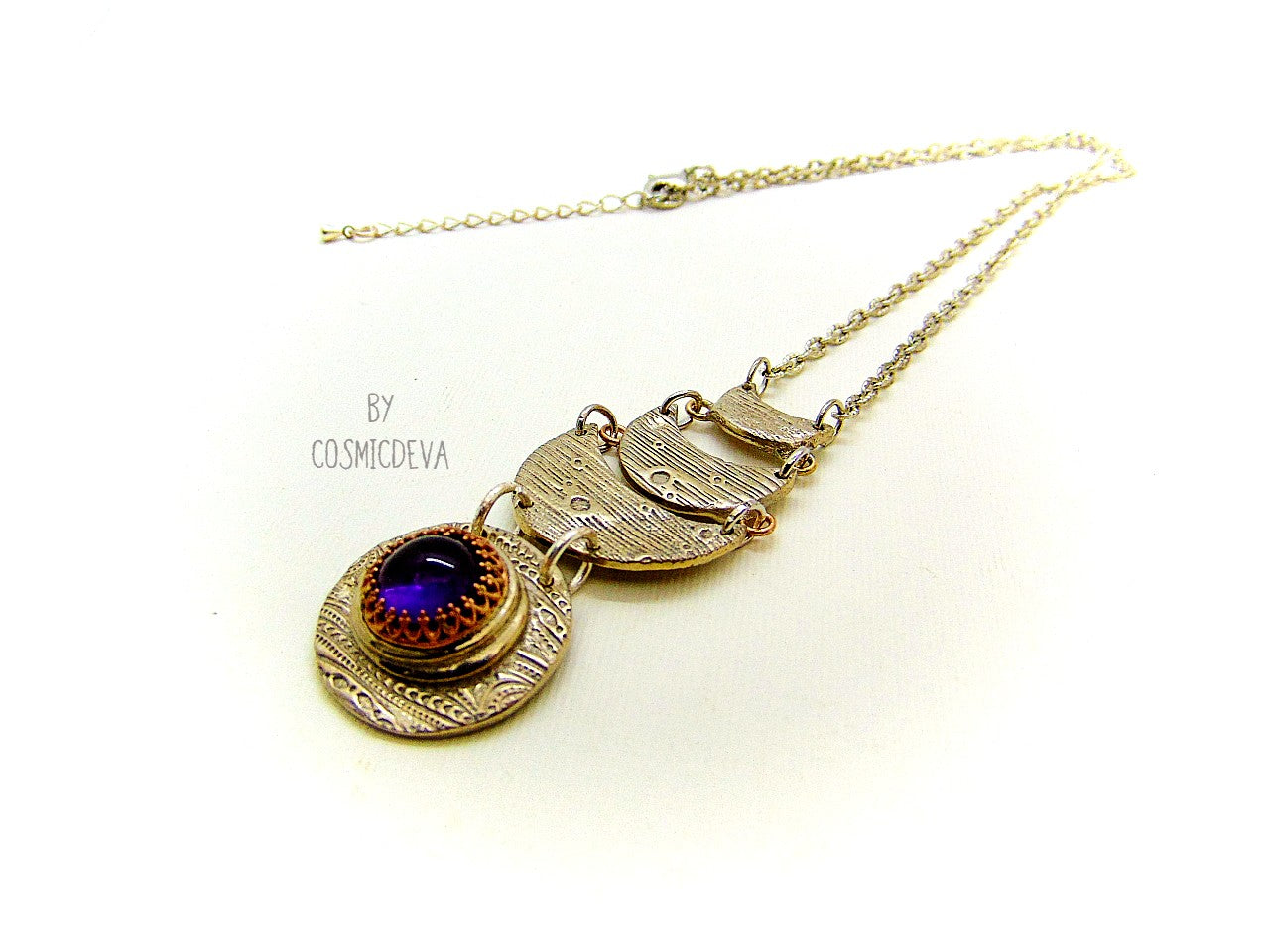 Beautiful purple silver moon phase necklace with a natural amethyst cabochon as a focal point. This silver bronze crescent moon pendant was completely hand formed and kiln fired. Silver bronze has the look of sterling silver but for a more affordable price. The moon pendant suspends from an 18 inch – 20-inch-long chain.