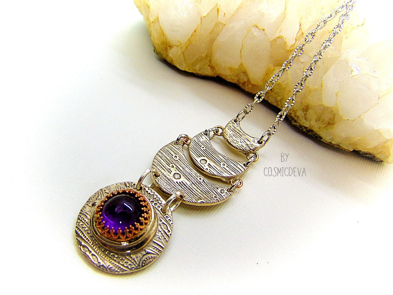 Beautiful purple silver moon phase necklace with a natural amethyst cabochon as a focal point. This silver bronze crescent moon pendant was completely hand formed and kiln fired. Silver bronze has the look of sterling silver but for a more affordable price. The moon pendant suspends from an 18 inch – 20-inch-long chain.