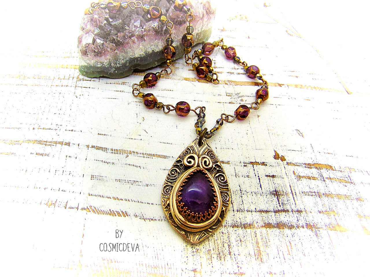 This unique Amethyst Pendant Necklace is an exquisite combination of modern and vintage. Hand sculptured in solid bronze with an elegant swirl texture and natural amethyst gemstone, its Boho gypsy style is complemented with a complete handmade rosary wire chain of purple gold faceted Czech glass beads.