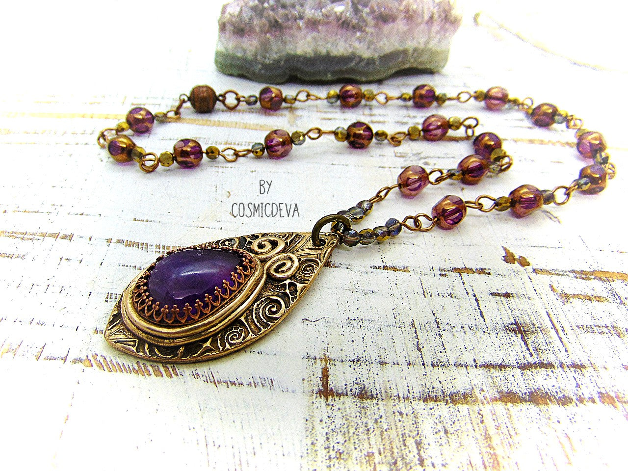 This unique Amethyst Pendant Necklace is an exquisite combination of modern and vintage. Hand sculptured in solid bronze with an elegant swirl texture and natural amethyst gemstone, its Boho gypsy style is complemented with a complete handmade rosary wire chain of purple gold faceted Czech glass beads.