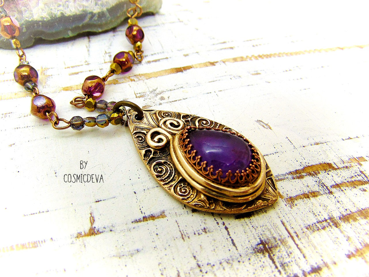 This unique Amethyst Pendant Necklace is an exquisite combination of modern and vintage. Hand sculptured in solid bronze with an elegant swirl texture and natural amethyst gemstone, its Boho gypsy style is complemented with a complete handmade rosary wire chain of purple gold faceted Czech glass beads.