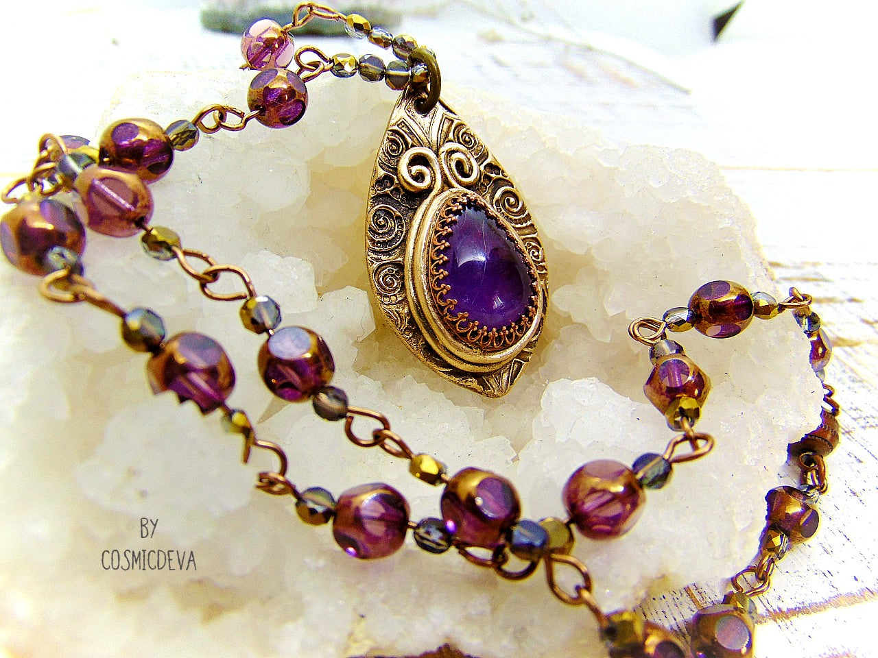 This unique Amethyst Pendant Necklace is an exquisite combination of modern and vintage. Hand sculptured in solid bronze with an elegant swirl texture and natural amethyst gemstone, its Boho gypsy style is complemented with a complete handmade rosary wire chain of purple gold faceted Czech glass beads.