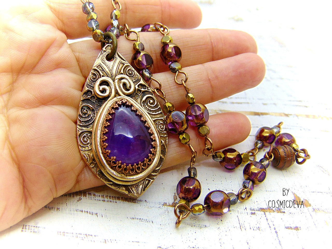 This unique Amethyst Pendant Necklace is an exquisite combination of modern and vintage. Hand sculptured in solid bronze with an elegant swirl texture and natural amethyst gemstone, its Boho gypsy style is complemented with a complete handmade rosary wire chain of purple gold faceted Czech glass beads.