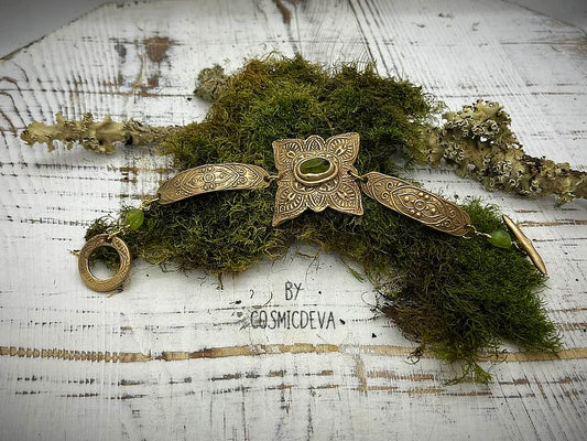 Feel enchanted by the earthy vibes of this Elven Bronze Medallion Bracelet with Raw Green Peridot. Hand formed with love, this medieval elven style bracelet is adorned with natural raw green peridot gemstones and a gracefully crafted toggle clasp..