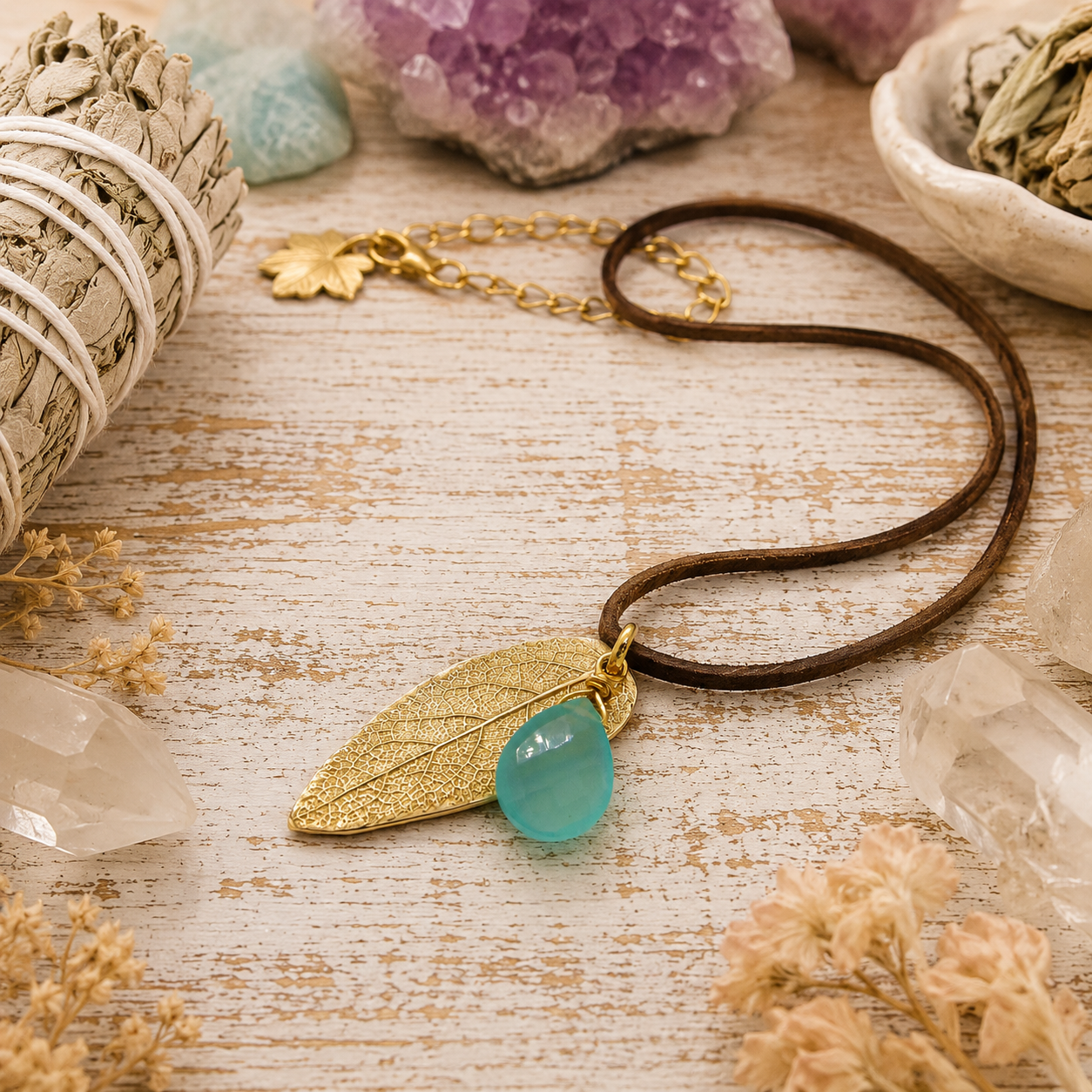Handmade bronze sage leaf necklace with aqua blue chalcedony gemstone and brown leather cord. Unique botanical boho jewelry inspired by nature.
