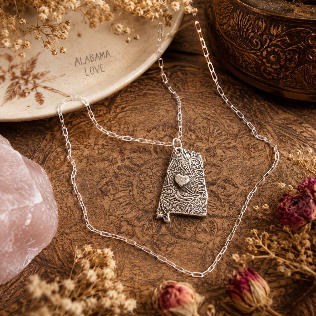 Shine your love for Alabama with this stunningly handcrafted and kiln-fired sterling silver necklace, featuring a delicate Alabama-shaped pendant with a heart in the center. Show off your state pride with a unique and fashionable piece of jewelry that is hallmarked as sterling silver and signed by CosmicDeva. Alabama love never looked so beautiful!