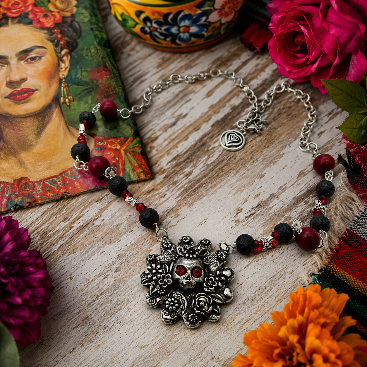 Cherish Mexican folk art with this unique Frida Kahlo sugar skull necklace, featuring a silver bronze floral pendant accented with garnet gemstones, roses, leaves and hearts.