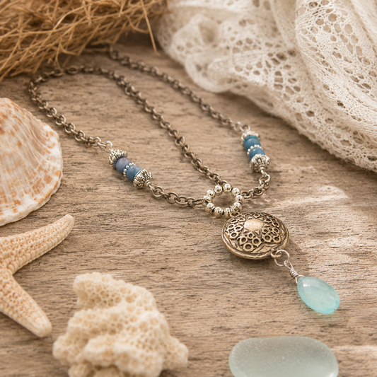 Handmade silver bronze mandala lentil pendant featuring an aqua blue chalcedony dangle, Brazilian aquamarine beads and Tibetan silver accents. A unique boho artisan necklace, adjustable from 18–20 inches.