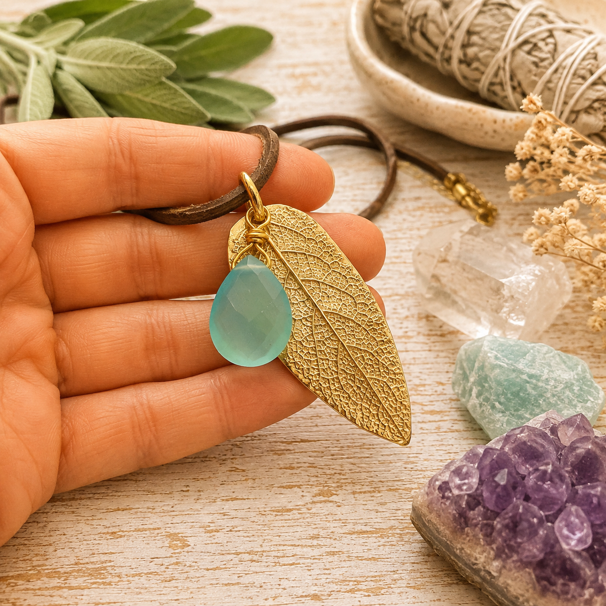 Handmade bronze sage leaf necklace with aqua blue chalcedony gemstone and brown leather cord. Unique botanical boho jewelry inspired by nature.