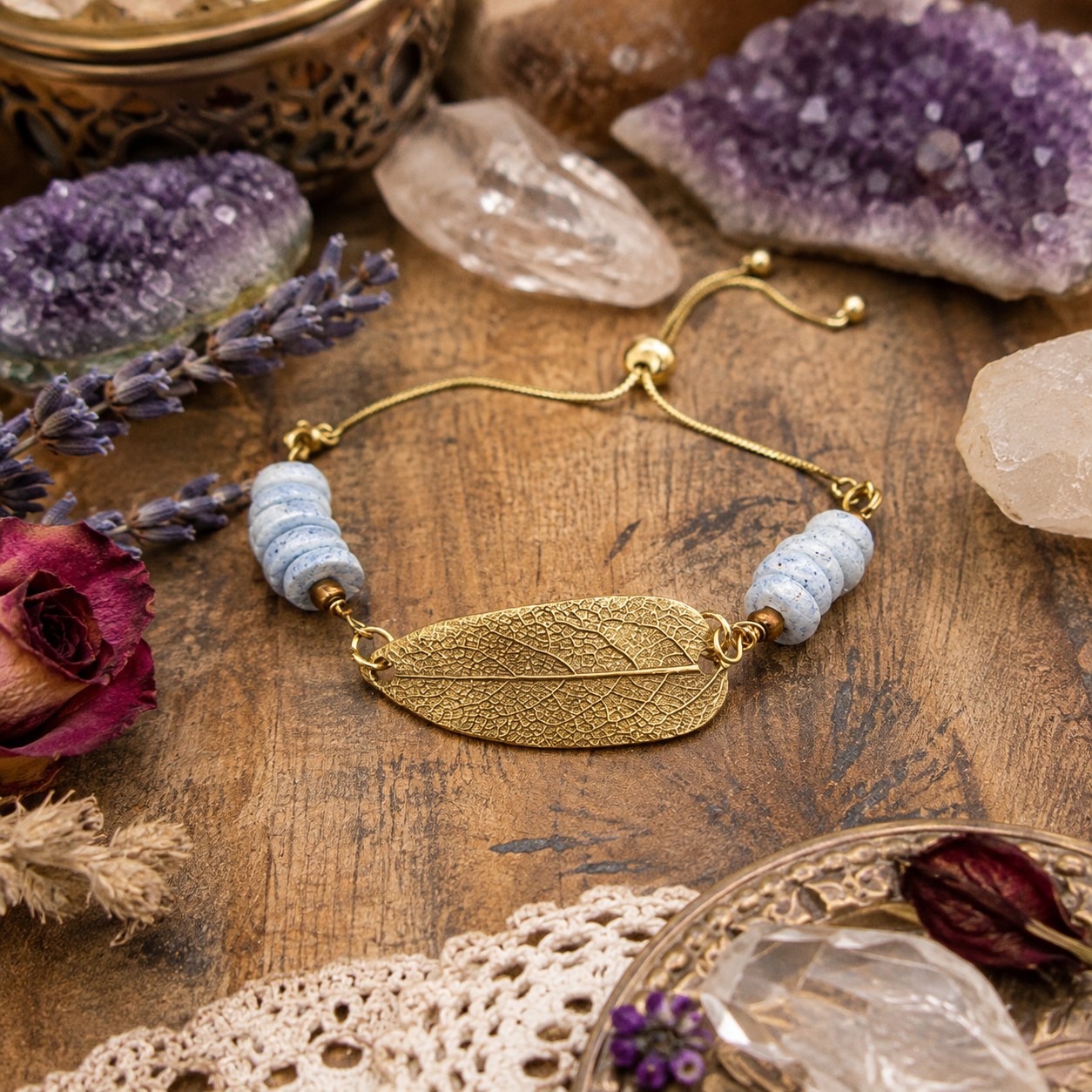 Handmade gold bronze sage leaf bracelet featuring a real botanical leaf imprint, Fair Trade aqua Ashanti glass beads and an adjustable slide clasp. By cosmicdeva 
