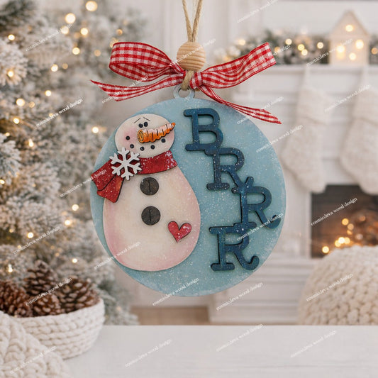 Add whimsical charm to your tree with our laser-cut Snowman Wood Ornament. Hand-painted with a red scarf and "Brrr" detail. High-quality 3.5" birch wood decor. Shop now!