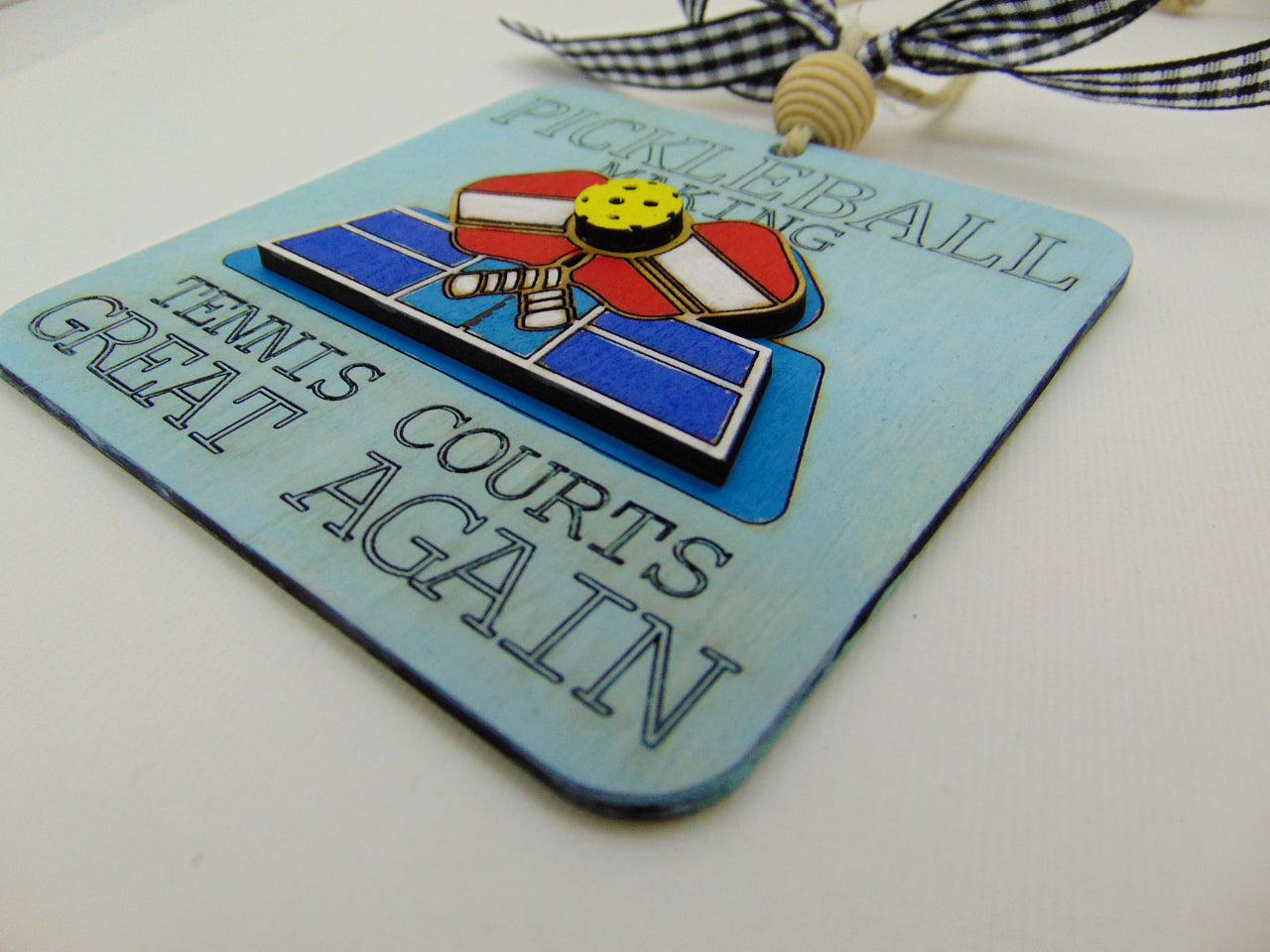 Celebrate the sport you love with this handcrafted Pickleball Ornament featuring the engraved phrase “Pickleball making tennis courts great again” and a 3D layered wood court with crossed paddles. Laser cut, hand painted, double sided, and gift ready—perfect for pickleball players, fans, and holiday décor.