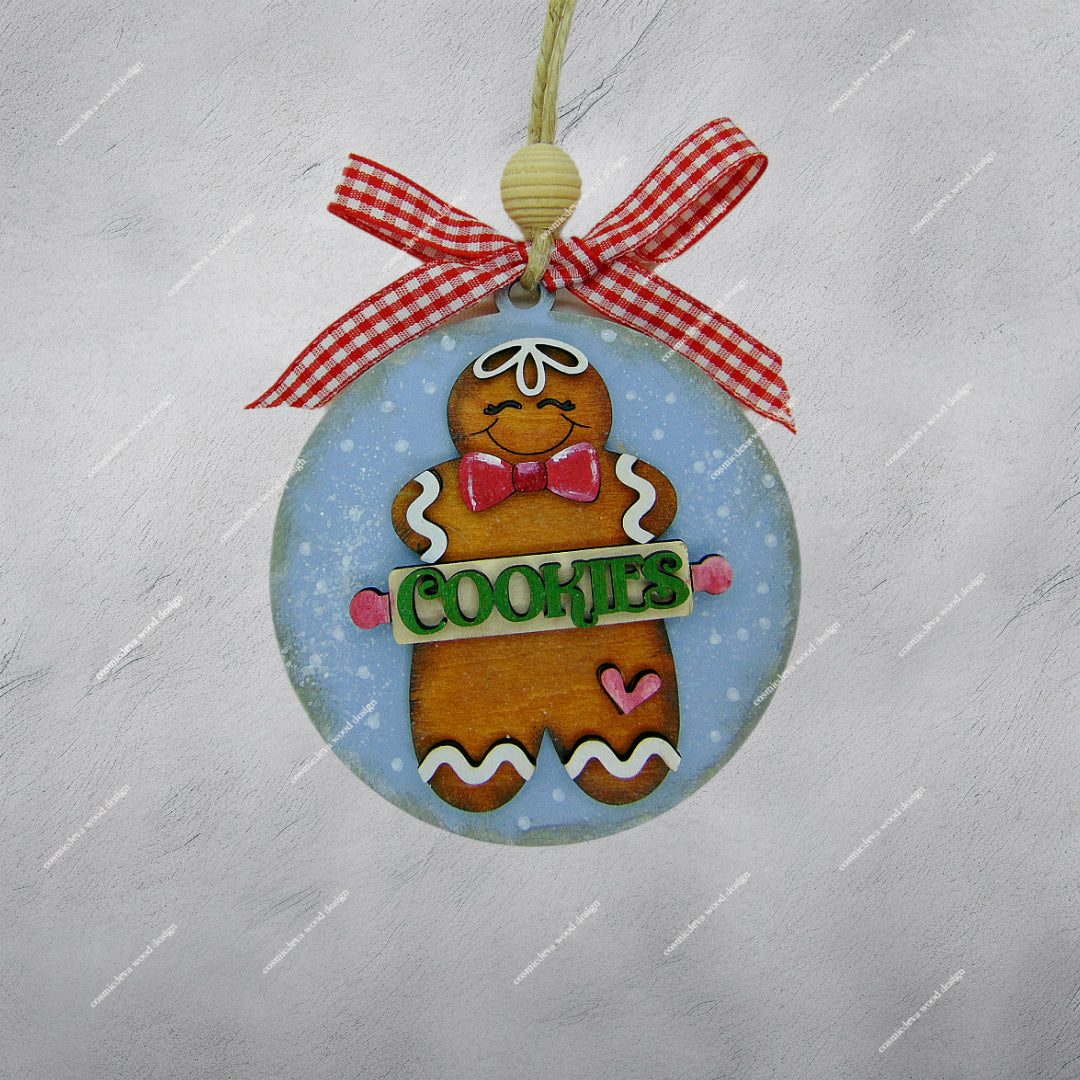 Hand painted wooden gingerbread man Christmas ornament with rolling pin “Cookies” cut out, blue sprinkle background, jute twine, wood bead, and checkered bow. Cute handmade holiday décor for bakers and cookie lovers.
