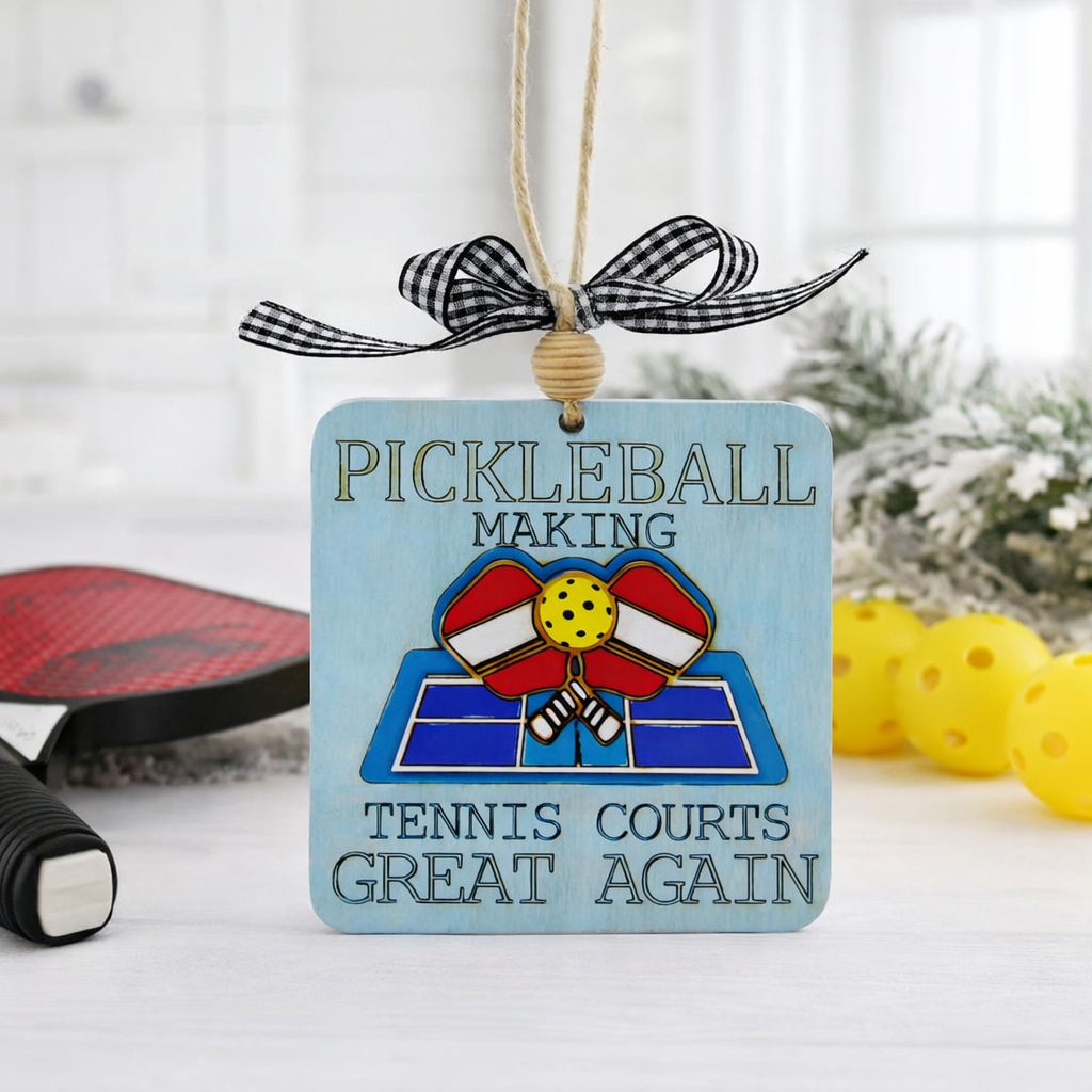 Celebrate the sport you love with this handcrafted Pickleball Ornament featuring the engraved phrase “Pickleball making tennis courts great again” and a 3D layered wood court with crossed paddles. Laser cut, hand painted, double sided, and gift ready—perfect for pickleball players, fans, and holiday décor.