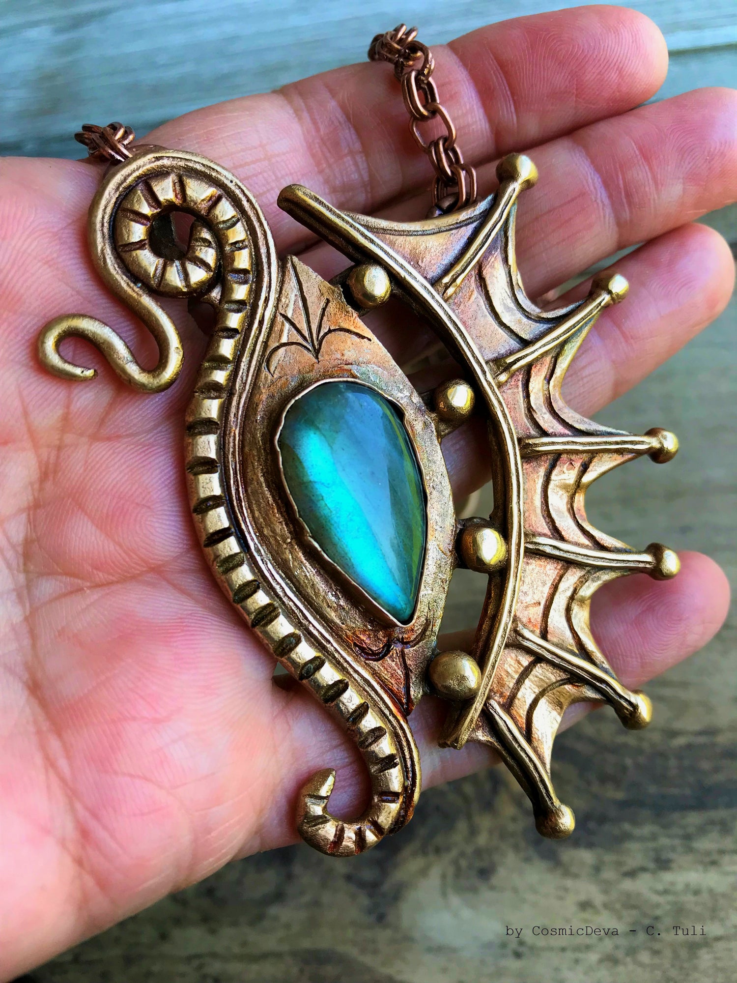 The Dragon is often seen as the guardian of a treasure. The treasure symbolizes you. This beautifully hand sculptured, carved, forged and kiln fired bronze pendant necklace symbolizes the Eye of a Dragon featuring a magical mystical shimmering labradorite gemstone. The reverse of the pendant is signed by the artist and carries the CosmicDeva brand hallmark.- CosmicDeva