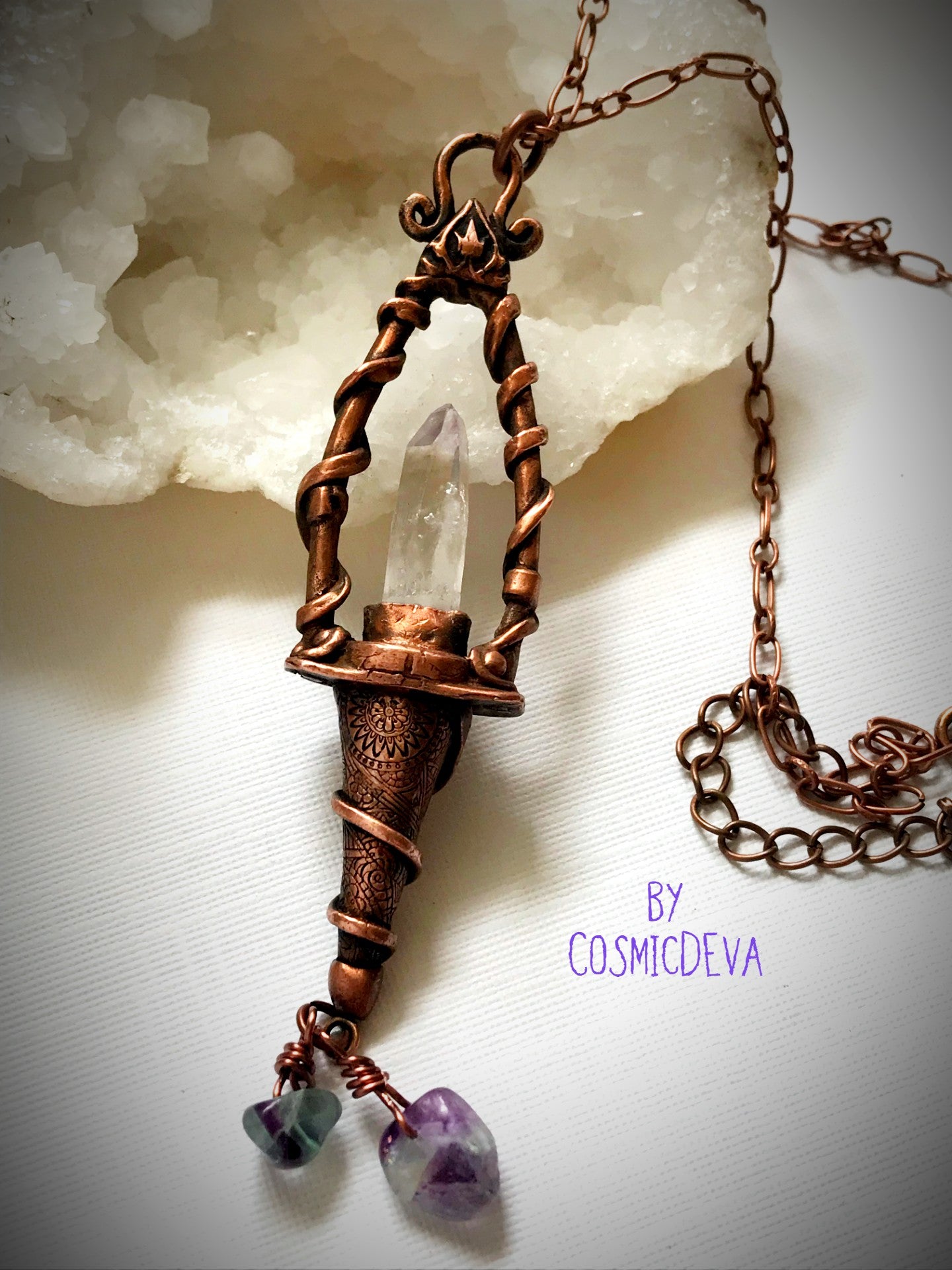 Weave a little magic into your wardrobe with this stunning magickal copper lantern necklace. Featuring a hand-sculpted, warm-glowing copper pendulum adorned with a super-clear Vera Cruz amethyst crystal point, plus two fluoride gemstones, it's a captivating conversation piece that will ignite your imagination. Suspended from an adjustable 21" copper chain, the oxidized finish and wax seal create a rich, deep warmth that will have you looking spell-bindingly beautiful. - CosmicDeva