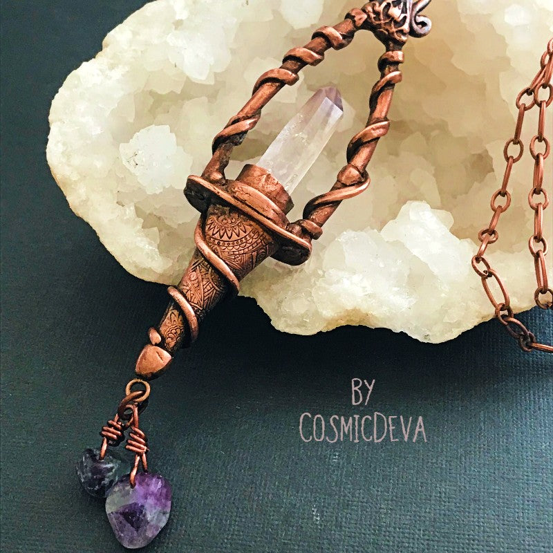Weave a little magic into your wardrobe with this stunning magickal copper lantern necklace. Featuring a hand-sculpted, warm-glowing copper pendulum adorned with a super-clear Vera Cruz amethyst crystal point, plus two fluoride gemstones, it's a captivating conversation piece that will ignite your imagination. Suspended from an adjustable 21" copper chain, the oxidized finish and wax seal create a rich, deep warmth that will have you looking spell-bindingly beautiful.- CosmicDeva