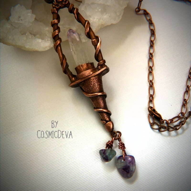 Weave a little magic into your wardrobe with this stunning magickal copper lantern necklace. Featuring a hand-sculpted, warm-glowing copper pendulum adorned with a super-clear Vera Cruz amethyst crystal point, plus two fluoride gemstones, it's a captivating conversation piece that will ignite your imagination. Suspended from an adjustable 21" copper chain, the oxidized finish and wax seal create a rich, deep warmth that will have you looking spell-bindingly beautiful.- CosmicDeva