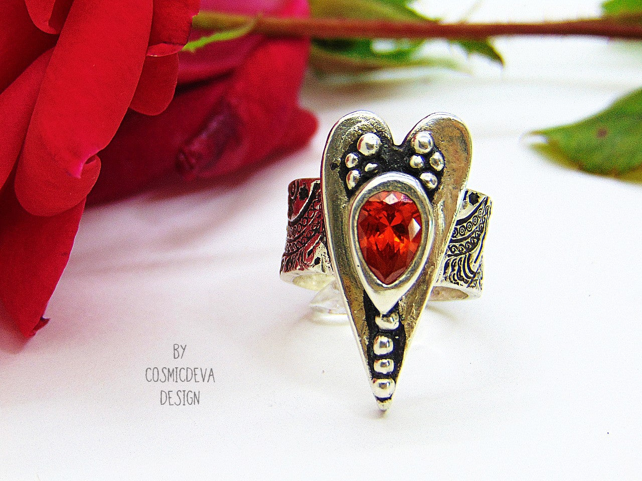 The heart is a symbol of love between two souls. This handcrafted wide ring shank sterling silver ring with floral texture featuring a large heart and 6 x 9 mm pear shaped red fire opal Cubic Zirconia gemstone . This Ring is made of pure .950 sterling silver and hallmarked as it. 