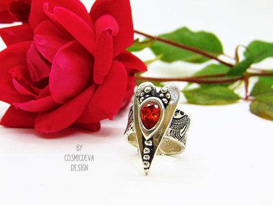 The heart is a symbol of love between two souls. This handcrafted wide ring shank sterling silver ring with floral texture featuring a large heart and 6 x 9 mm pear shaped red fire opal Cubic Zirconia gemstone . This Ring is made of pure .950 sterling silver and hallmarked as it. 