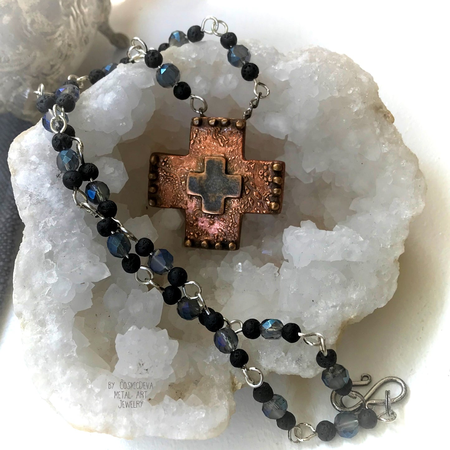 Adorn your faith with this beautiful Copper Cross Rosary Necklace. Handcrafted with love, this necklace features a solid pure copper cross pendant draped over a stunning rosary of .925 sterling silver-plated wire and shimmering blue Czech beads with petite black lava beads. The perfect choice for those seeking a boho-inspired way to wear their faith proudly. - CosmicDeva