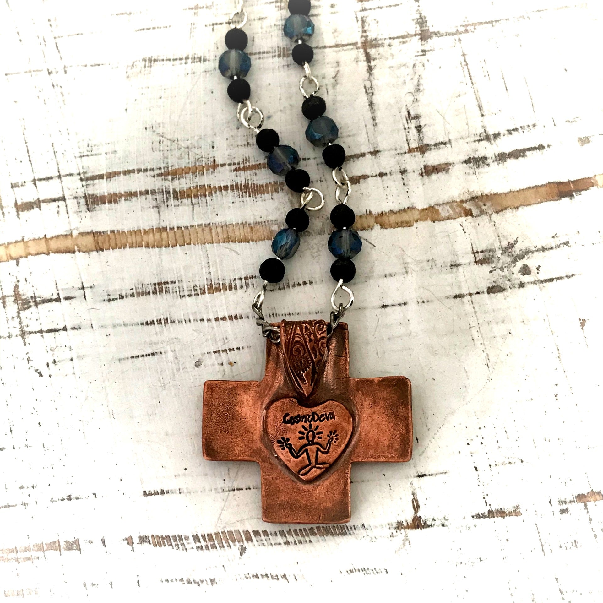 Copper Cross Rosary Necklace, Boho Faith Jewelry. A beautiful completely handmade and kiln fired western cross pendant made of solid pure copper dangles from a rosary necklace with gorgeous petite blue Czech beads and black lava beads. The handmade rosary chain is made of .925 sterling silver plated wire with sparkling blue faceted Czech glass beads and small black volcanic lava stone beads. A pretty little heart is stamped with the artist’s logo on the backside adding a lovely detail. - CosmicDeva