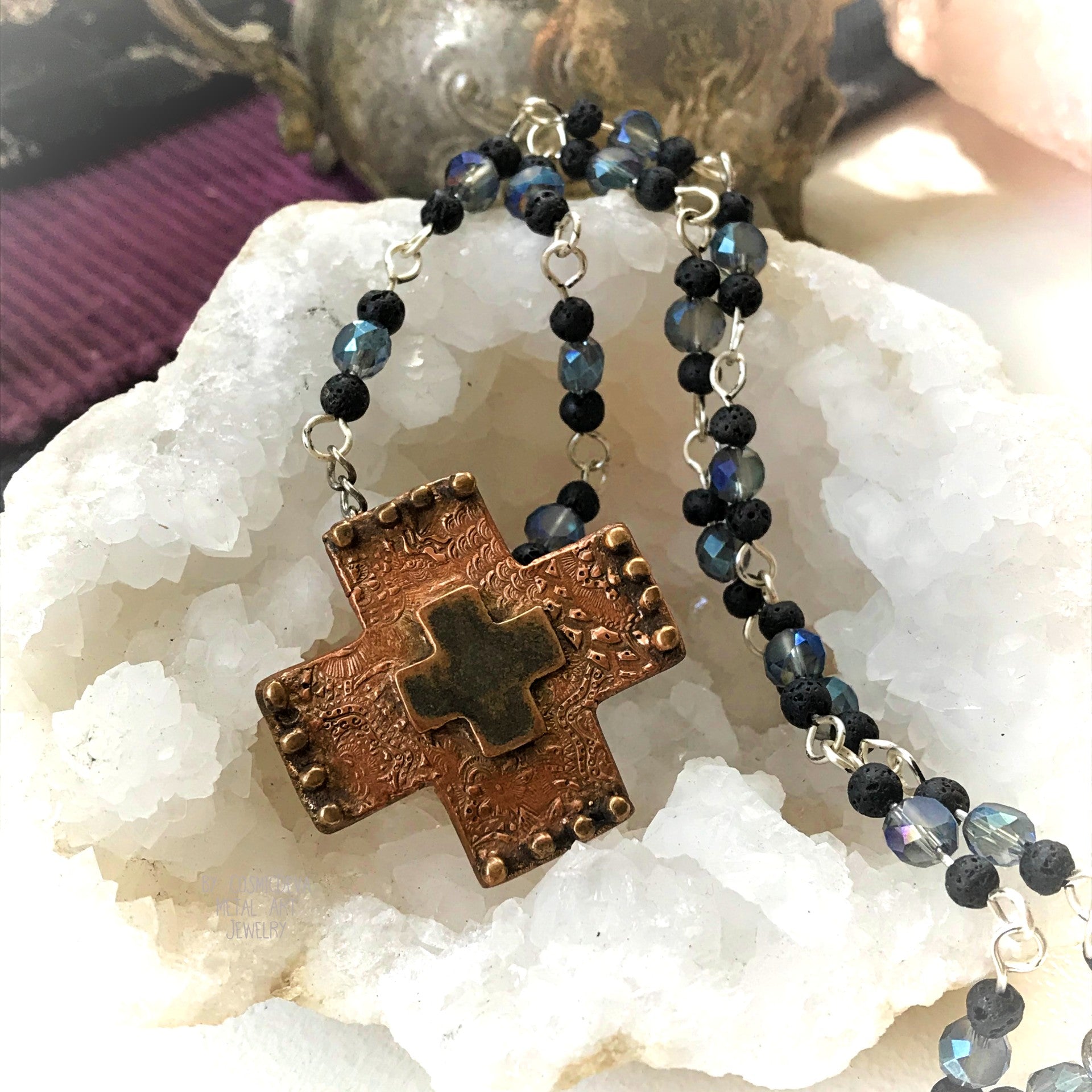 Copper Cross Rosary Necklace, Boho Faith Jewelry. A beautiful completely handmade and kiln fired western cross pendant made of solid pure copper dangles from a rosary necklace with gorgeous petite blue Czech beads and black lava beads. The handmade rosary chain is made of .925 sterling silver plated wire with sparkling blue faceted Czech glass beads and small black volcanic lava stone beads. A pretty little heart is stamped with the artist’s logo on the backside adding a lovely detail. - CosmicDeva