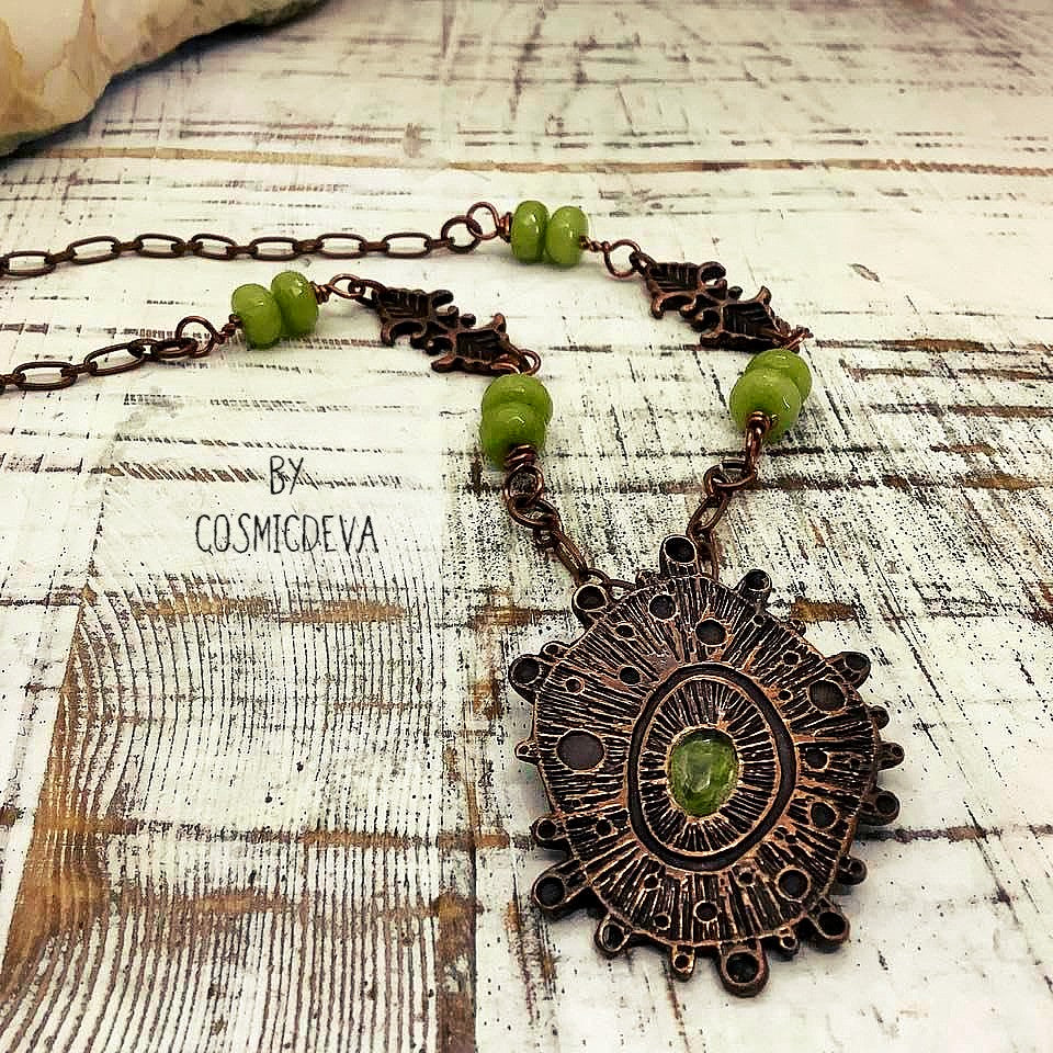 Draw attention with this unique one-of-a-kind handmade copper pendant necklace, featuring a stunning peridot gemstone at its center. Oxidized for a warm, deep finish and suspended by light olive-green jade beads, it's a magnificent piece of art that will add a special touch of glamour to any occasion. Wear it and make an unforgettable impression! CosmicDeva