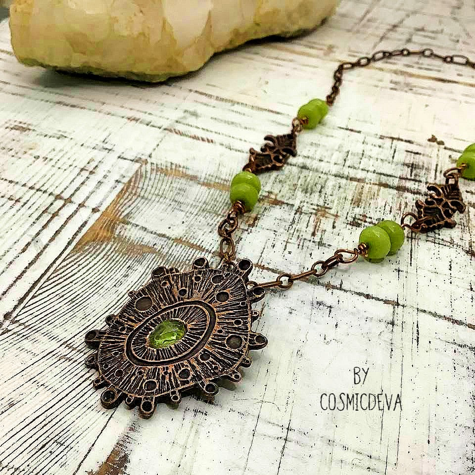 Draw attention with this unique one-of-a-kind handmade copper pendant necklace, featuring a stunning peridot gemstone at its center. Oxidized for a warm, deep finish and suspended by light olive-green jade beads, it's a magnificent piece of art that will add a special touch of glamour to any occasion. Wear it and make an unforgettable impression!- CosmicDeva