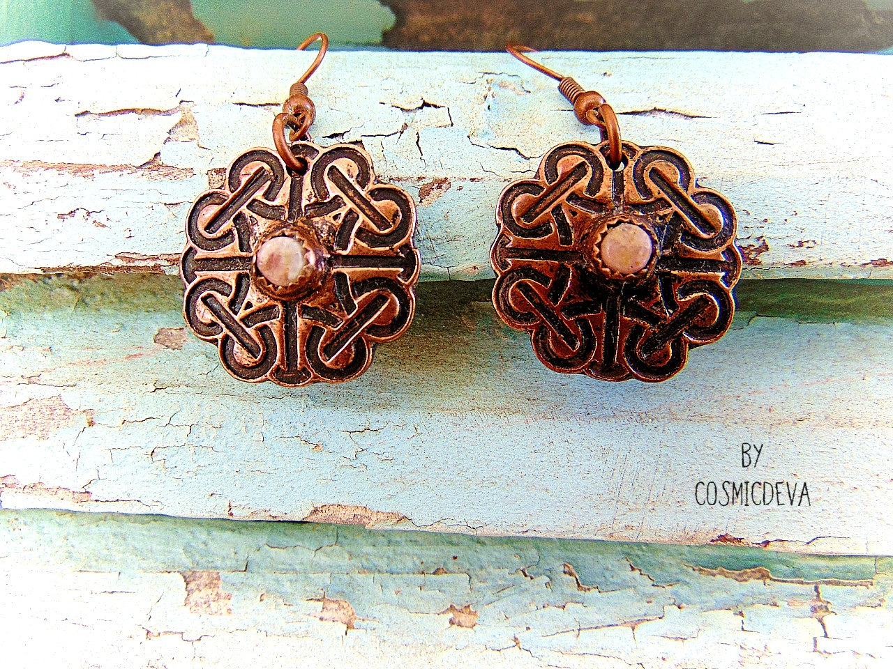 Handcrafted solid copper Celtic knot earrings featuring white natural tourmaline gemstones in the center. The Celtic knot is a significant symbol that is also referred to as the mystic or endless knot, and the symbolism behind it involves beginnings and endings