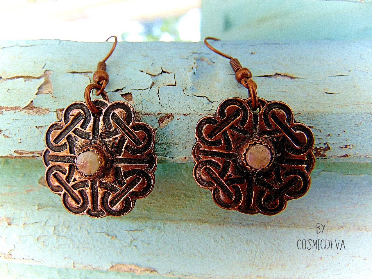 Handcrafted solid copper Celtic knot earrings featuring white natural tourmaline gemstones in the center. The Celtic knot is a significant symbol that is also referred to as the mystic or endless knot, and the symbolism behind it involves beginnings and endings