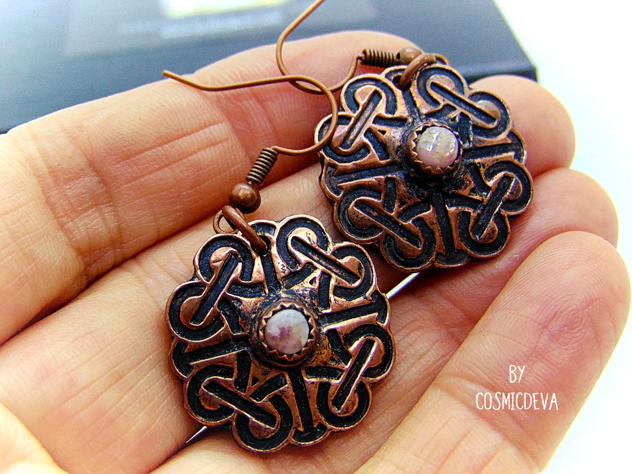 Handcrafted solid copper Celtic knot earrings featuring white natural tourmaline gemstones in the center. The Celtic knot is a significant symbol that is also referred to as the mystic or endless knot, and the symbolism behind it involves beginnings and endings