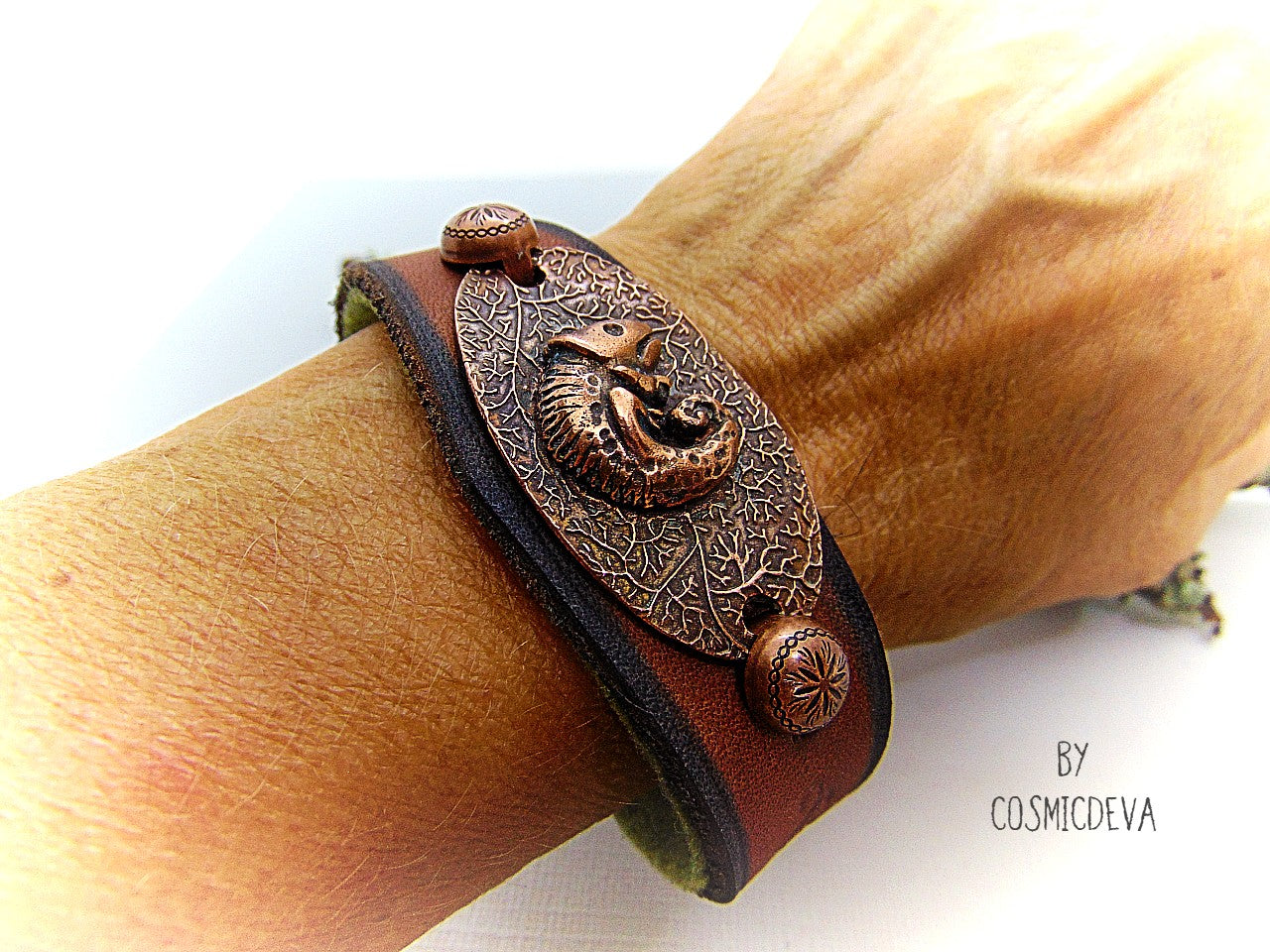 Unique handcrafted leather bracelet made of earthy brown dyed veg tan leather. The focal point is a hand sculptured solid copper chameleon on a textured solid copper base. The inside of the leather bracelet is lined with olive green felt for your comfort.