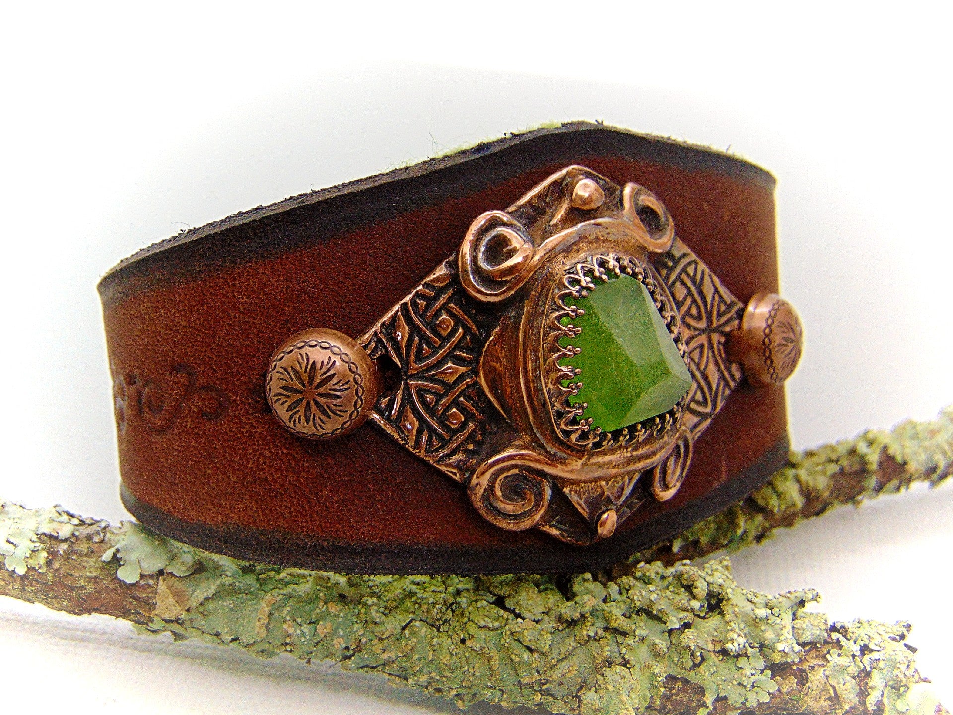 One of a kind handcrafted leather cuff bracelet made of hand cut earthy brown dyed veg tan leather. The focal point is a high quality natural raw green peridot gemstone in a bezel setting on a Celtic design textured solid copper base. The inside of the leather bracelet is lined with olive green felt for your comfort. Cosmicdeva