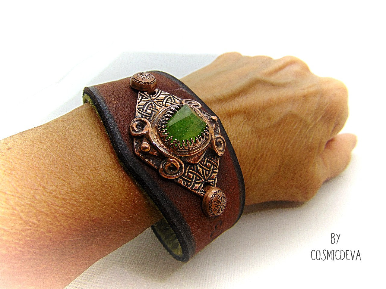 One of a kind handcrafted leather cuff bracelet made of hand cut earthy brown dyed veg tan leather. The focal point is a high quality natural raw green peridot gemstone in a bezel setting on a Celtic design textured solid copper base. The inside of the leather bracelet is lined with olive green felt for your comfort. Cosmicdeva