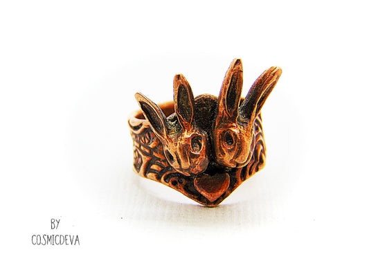 Love bunnies? Show your devotion with this gorgeous Copper Bunny Love Ring! Crafted by hand, it features two snuggled bunny heads with a heart in the middle, plus a textured shank and a heart on the back. One-of-a-kind and unique, this US Size 7.5 Ring is perfect for expressing your style and your bunny appreciation!