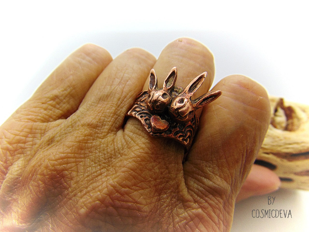 Love bunnies? Show your devotion with this gorgeous Copper Bunny Love Ring! Crafted by hand, it features two snuggled bunny heads with a heart in the middle, plus a textured shank and a heart on the back. One-of-a-kind and unique, this US Size 7.5 Ring is perfect for expressing your style and your bunny appreciation!