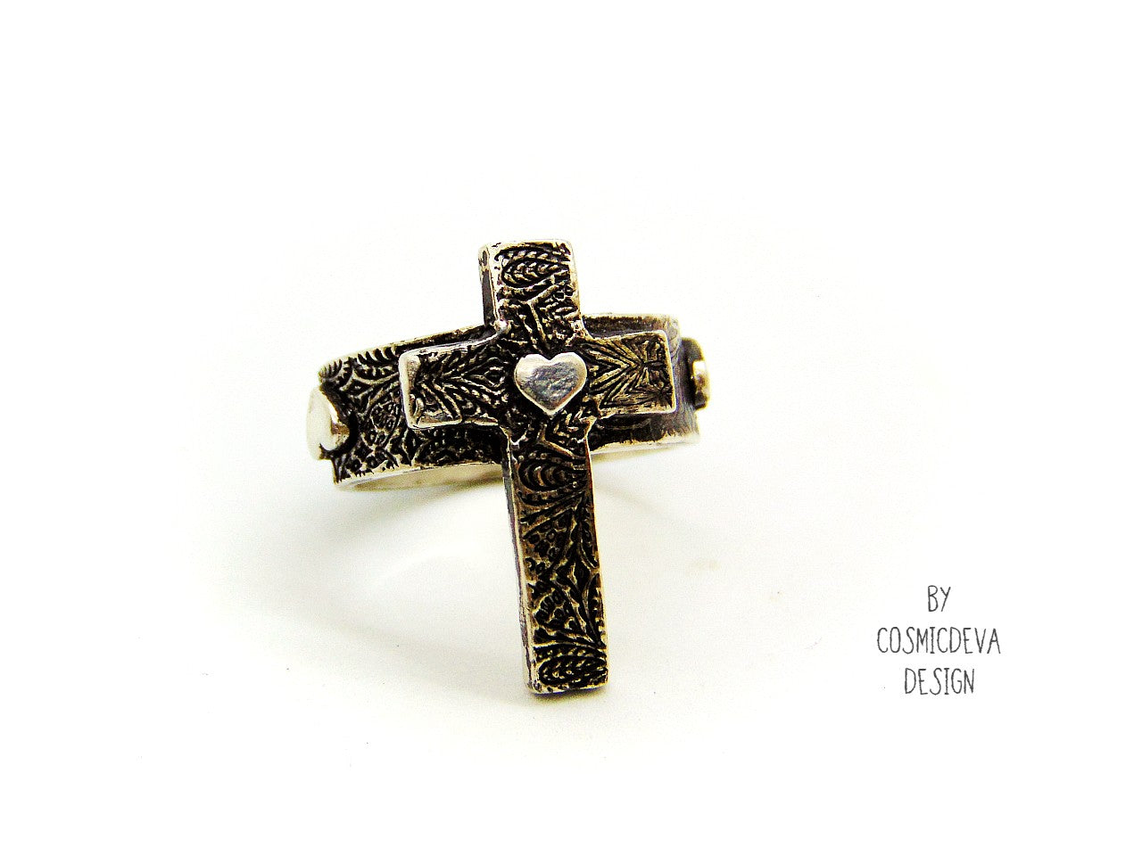 Completely handcrafted solid sterling silver cross ring. The surface of the ring features a rich oxidized textured cross with a heart in the center of the cross. The heart symbol in the center of the cross and on the sides of the ring shank is a reminder that Christ as a foundation is built on love – all the love we have for others should be unconditional in the same way he loves us. Love each other as I have loved you – John 15:12.